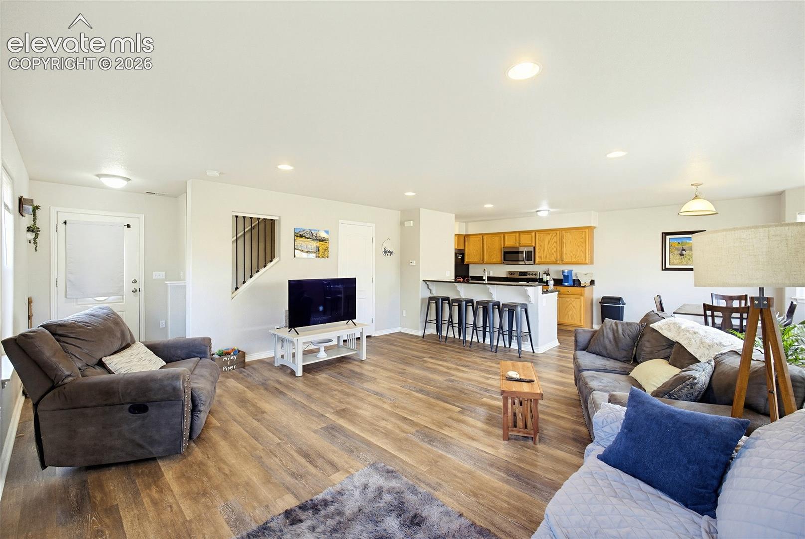Open-concept interior featuring wood-finish flooring, recessed lighting, and a kitchen peninsula with integrated seating