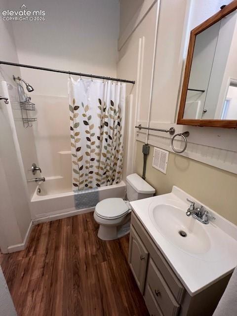 Full bathroom featuring a tub-shower combination, wood-finish flooring, vanity with a white countertop and integrated sink, wall-mounted wooden medicine cabinet, and polished chrome fixtures
