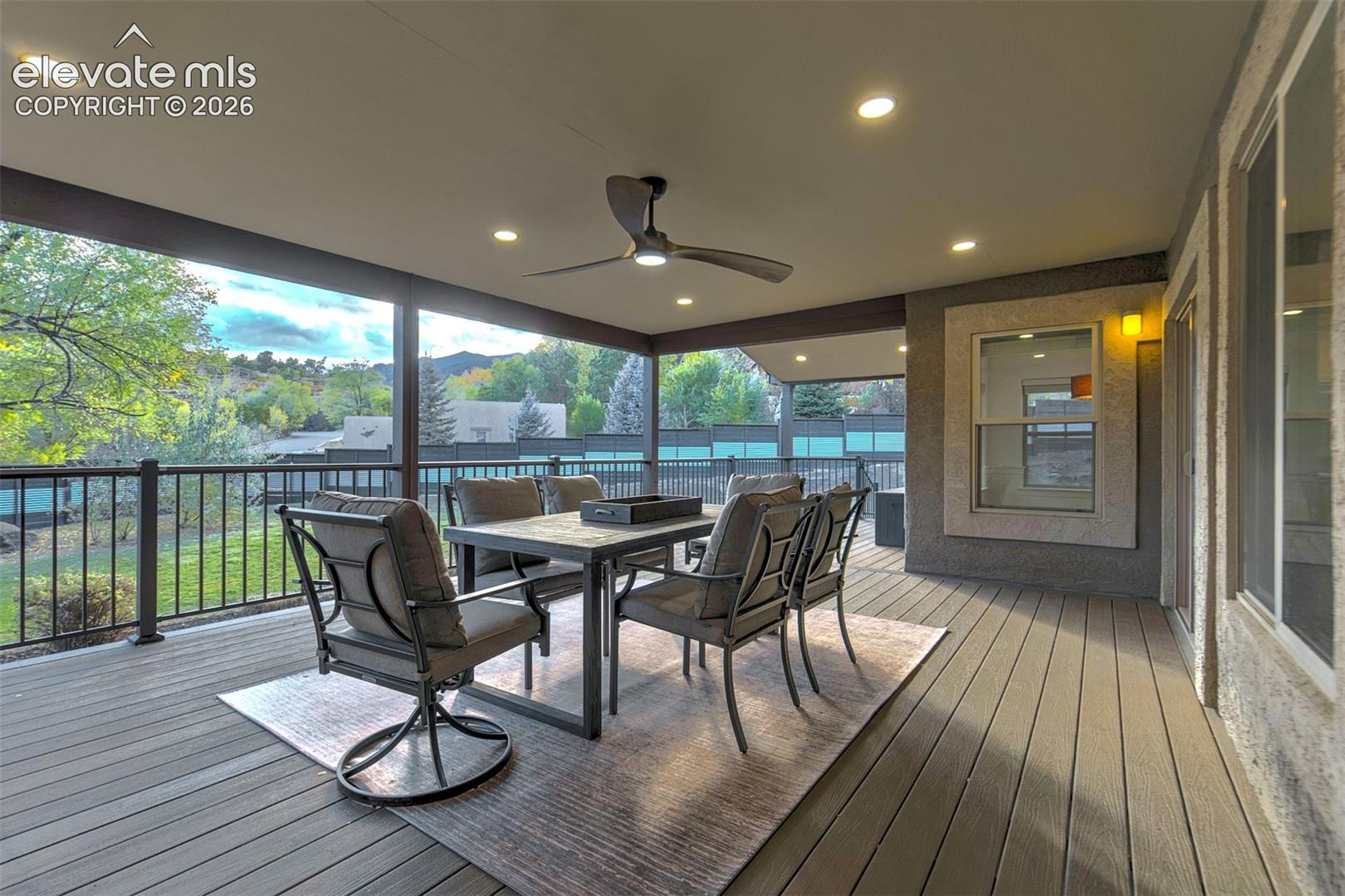 Covered patio featuring composite decking, recessed lighting, a ceiling fan, and a metal railing
