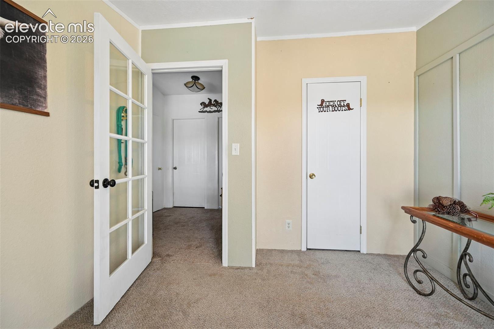 Bedroom #3 Interior featuring a French door with glass paneling, neutral wall tones, carpeted flooring, and white interior doors with metallic hardware