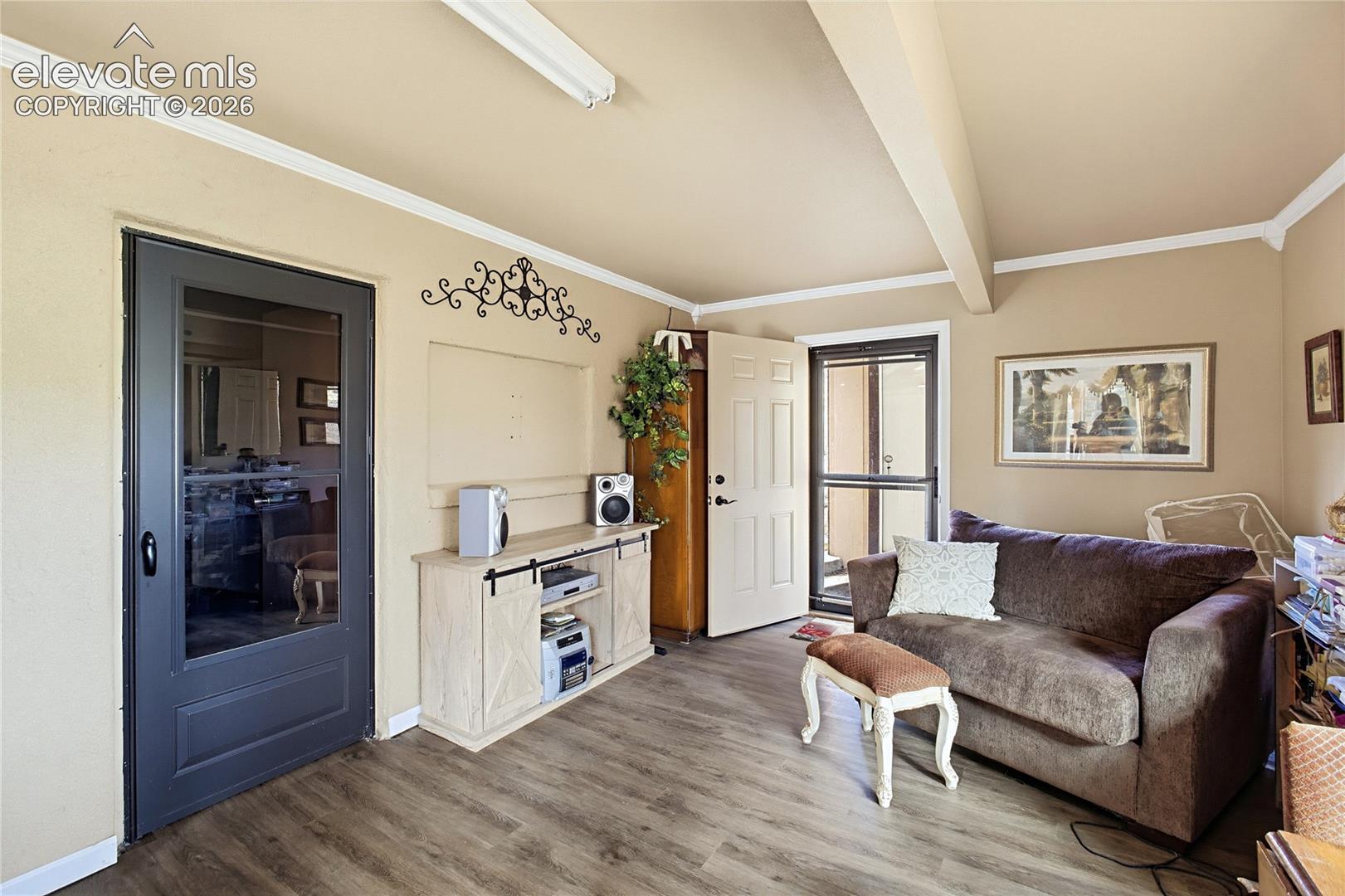 Wood-finish flooring, crown molding, a built-in recessed media nook, and a dual-pane glass-panel storm door