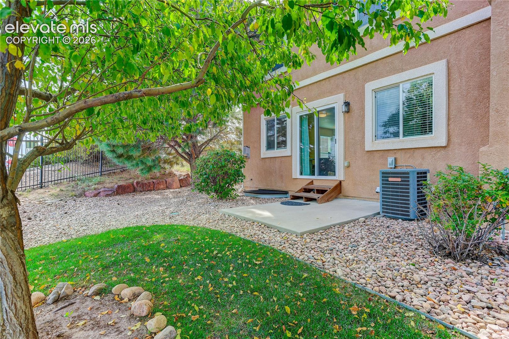 Back patio and back yard with kidney shaped grass area. 