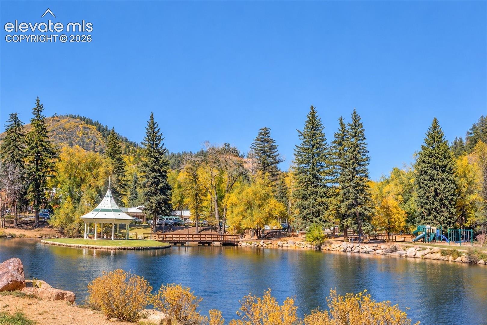 Grounds featuring a private pond, a central gazebo on an island, a wooden bridge, and mature evergreen and deciduous trees