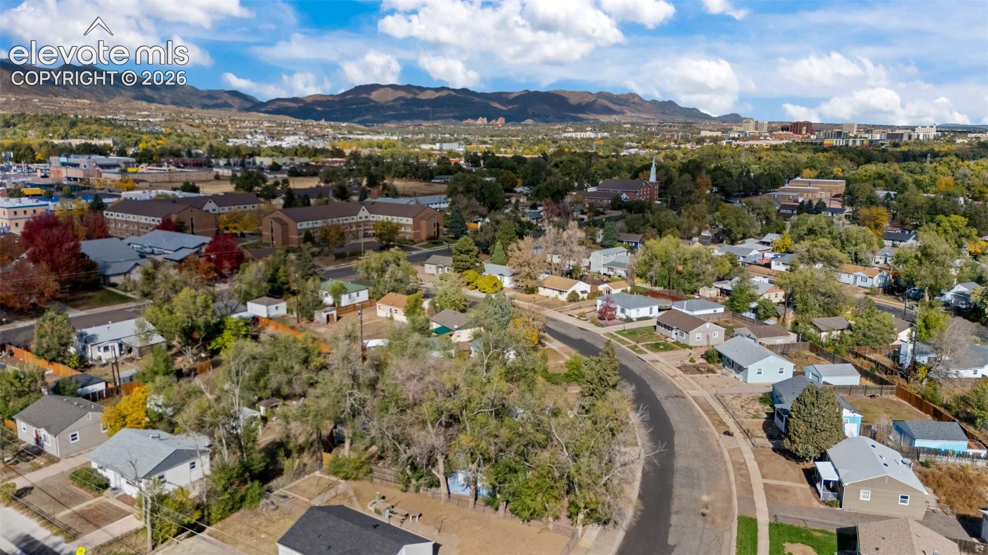Aerial perspective featuring mature trees, a curated residential street layout, and a prominent mountain range backdrop