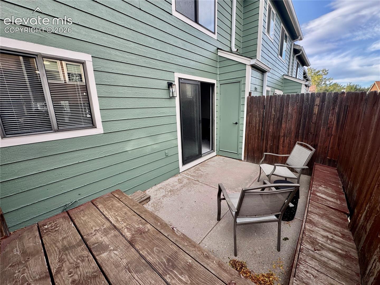 Private outdoor area featuring a concrete patio, horizontal wood-plank decking, and a wood privacy fence
