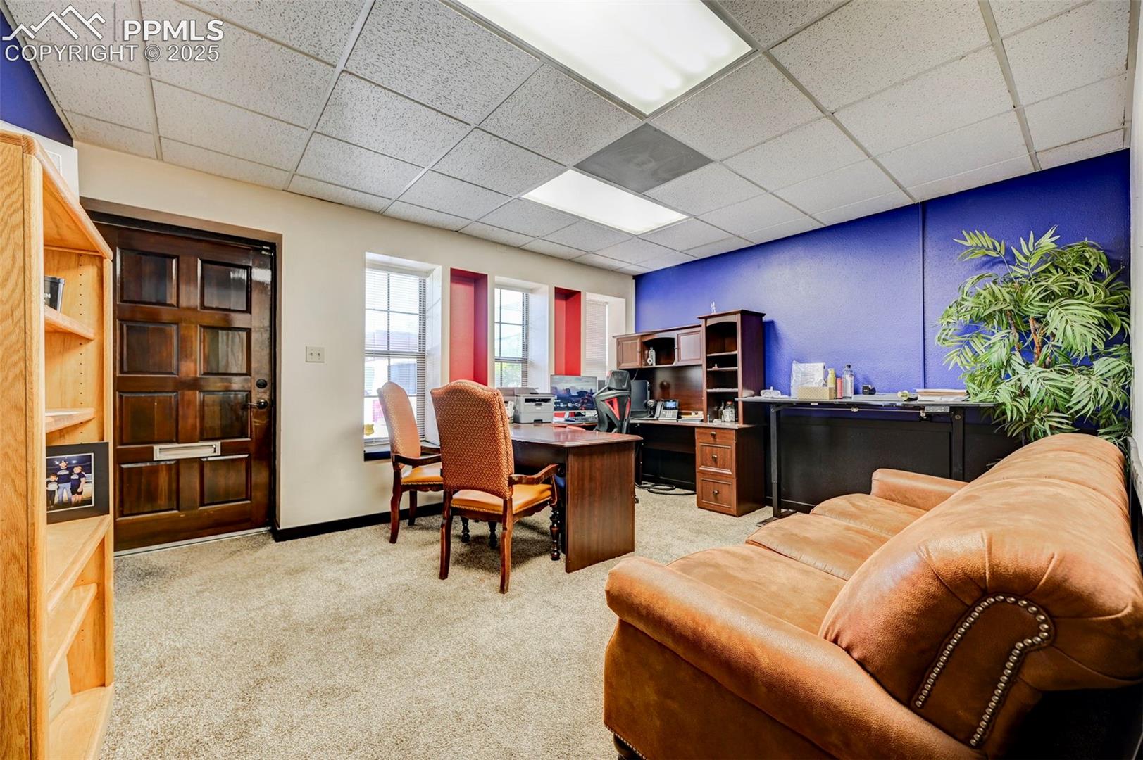 Office area featuring light carpet, a drop ceiling, and baseboards