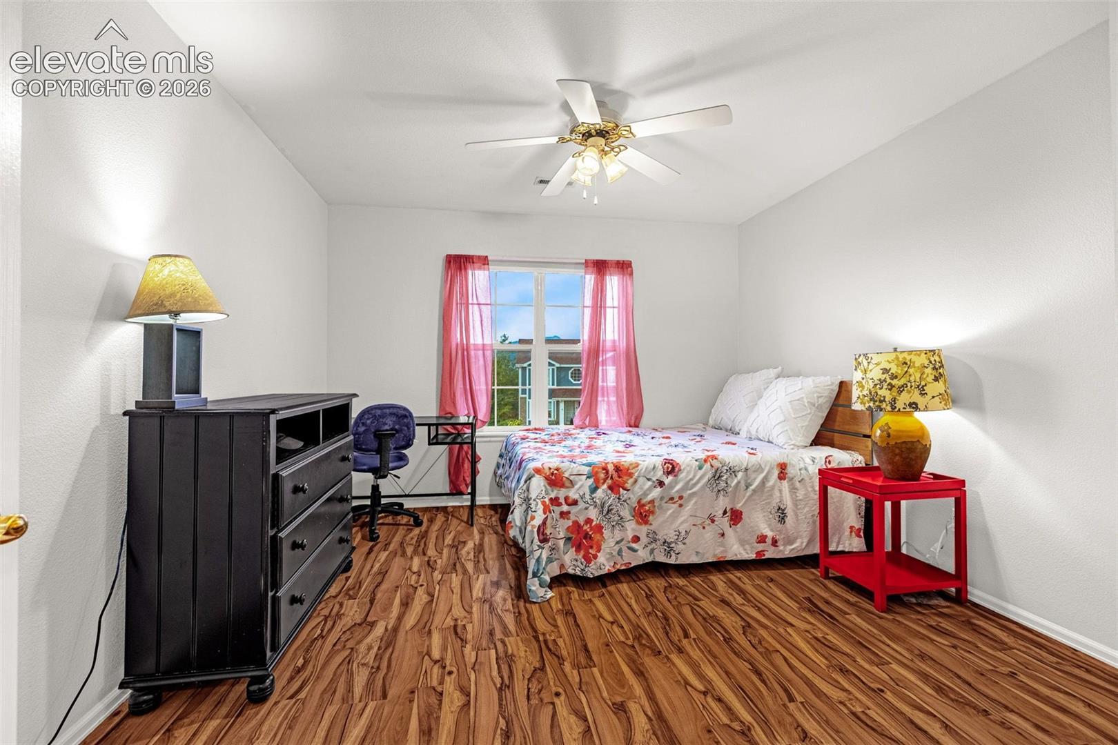 Wood-finish flooring, ceiling fan with integrated lighting, white painted walls, and a window with natural light