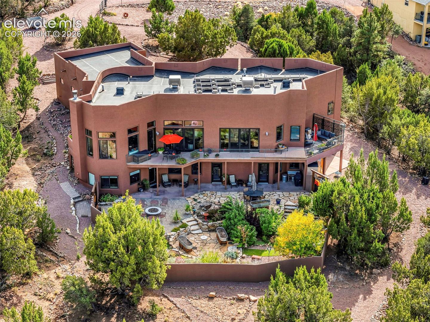 Pueblo-style exterior featuring a multi-level structure, a wraparound elevated balcony, and a multi-tiered flagstone patio