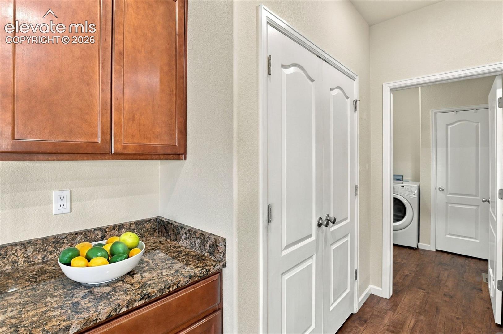 Wood-finish cabinetry, stone-texture countertop, double-panel interior doors, and wood-finish flooring