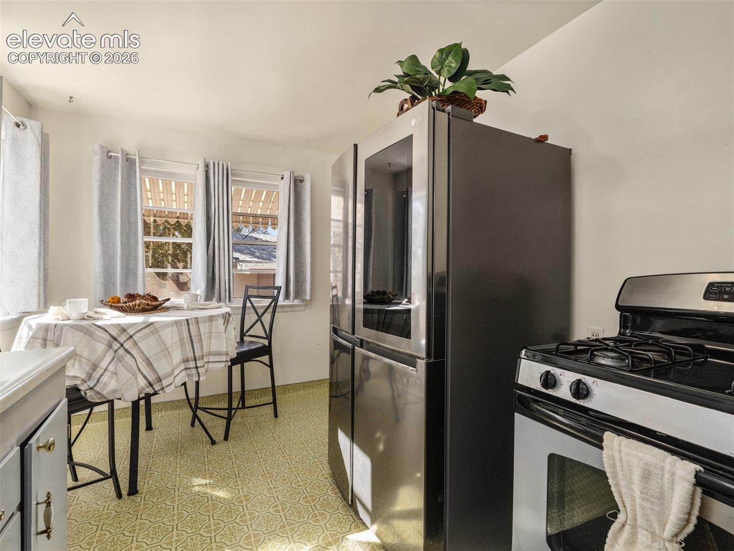 Stainless steel refrigerator with integrated window panel and stainless steel gas range with cooktop
