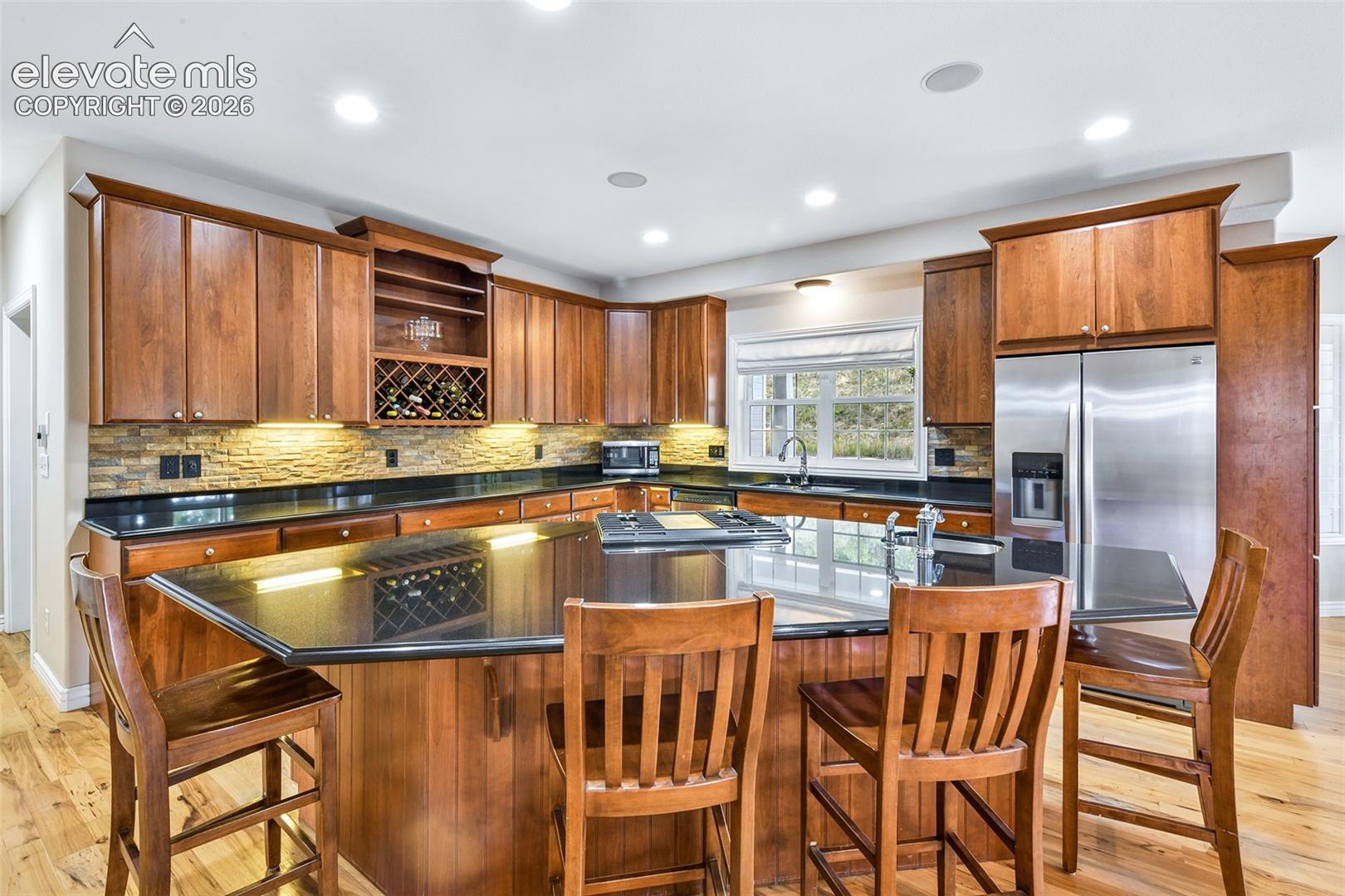 Gorgeous cherry cabinetry, and roomy center island with granite counters, vegetable sink, storage and loads of seating