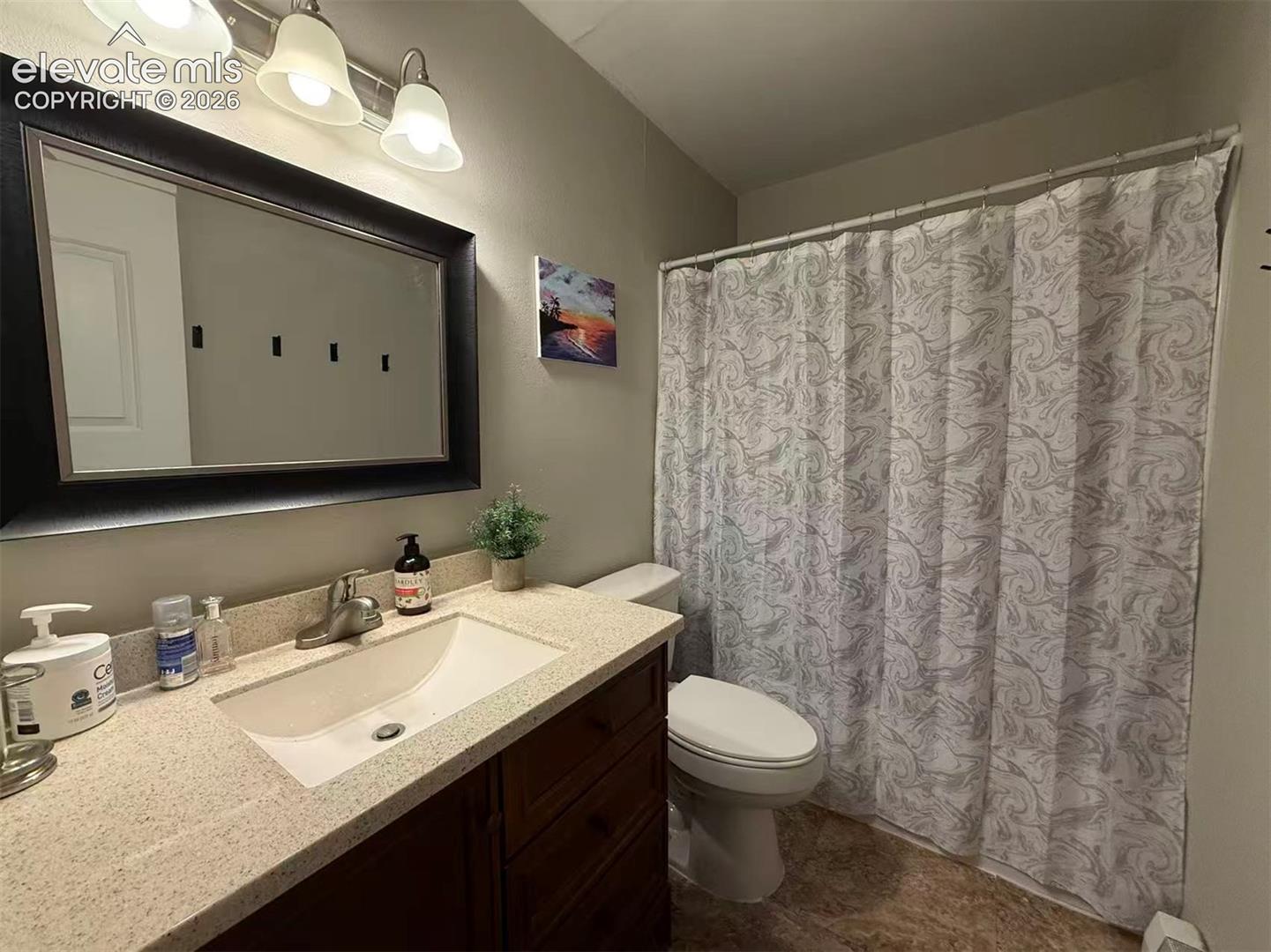 Vanity with a light-colored countertop, an undermount sink, and a framed mirror