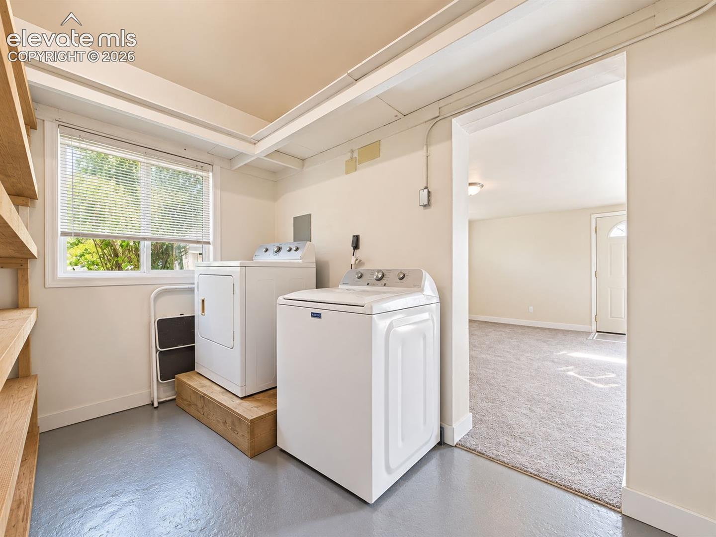 Dedicated laundry room featuring a washer and dryer, built-in wooden shelving, natural light, and convenient access to the adjoining family room