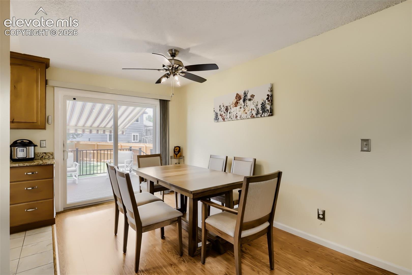 Dining area featuring wood-finish flooring, a ceiling fan with integrated lighting, and a sliding glass door