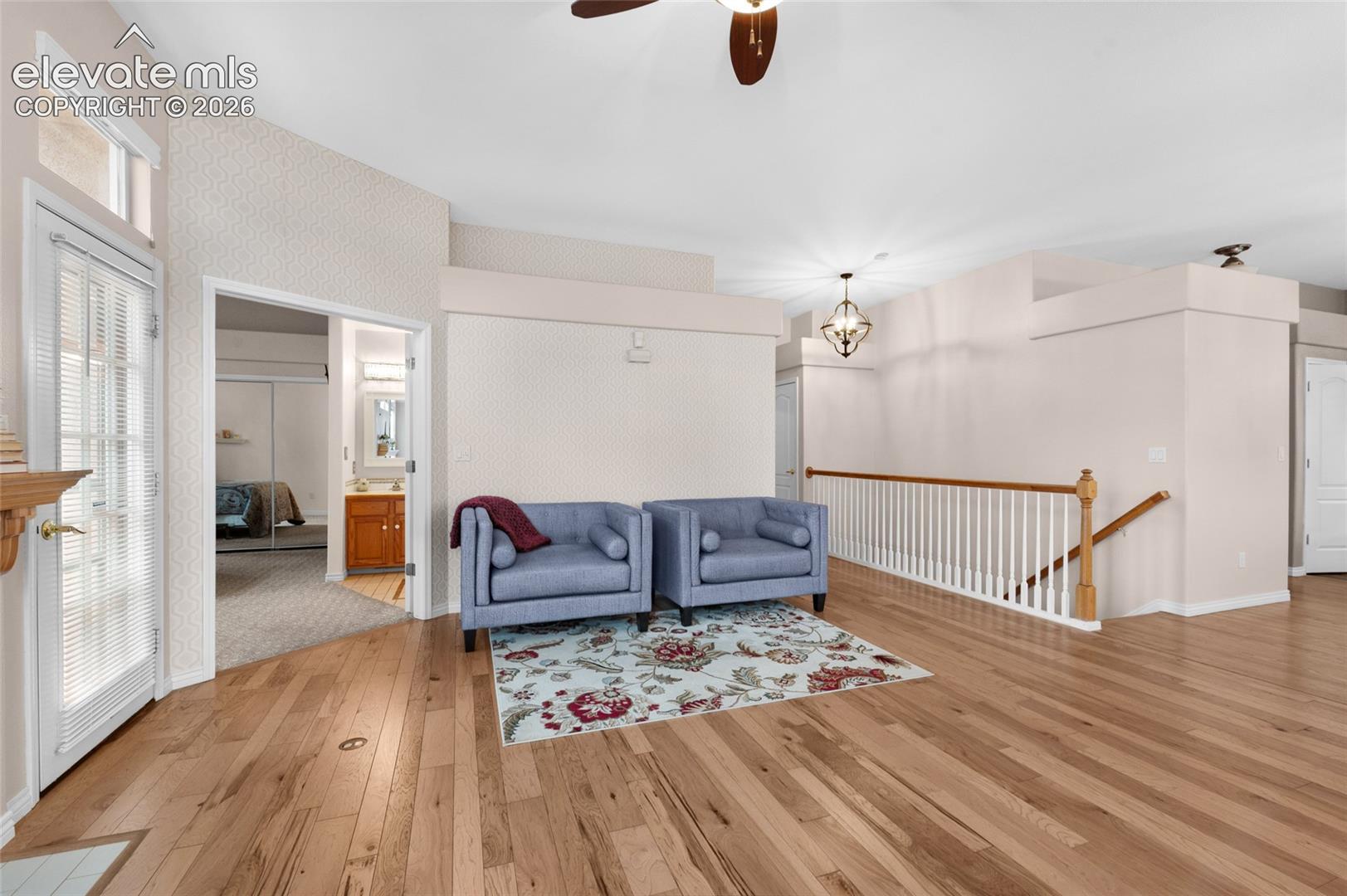 Wood-finish flooring, white spindle staircase railing with a wood-finish handrail, vaulted ceilings, and a glass-paneled exterior door