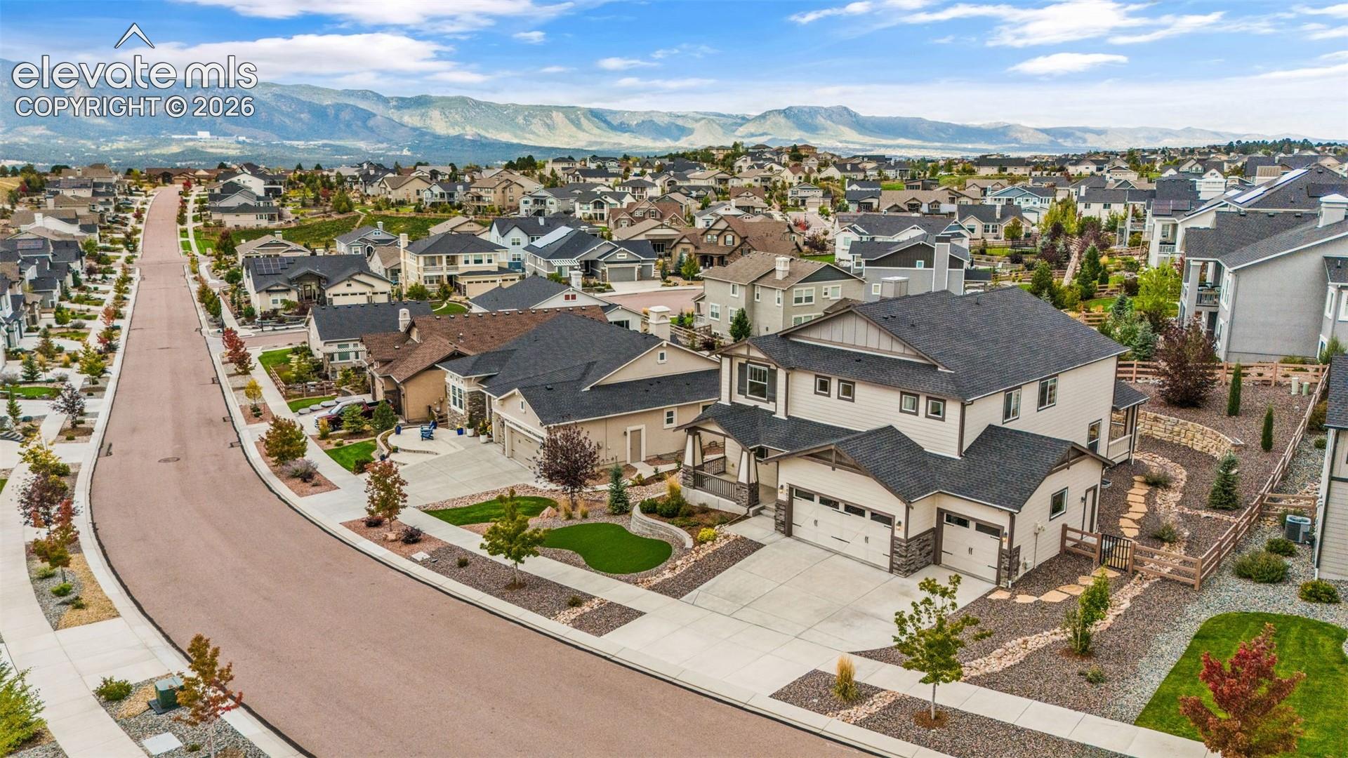 Exterior with a Three-car garage, stone accents, and a landscaped front yard that includes artificial turf