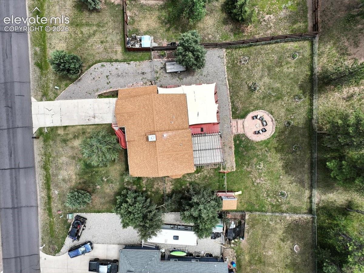 Aerial perspective of property featuring a concrete driveway, a paved circular hardscape area, a pergola, and perimeter fencing