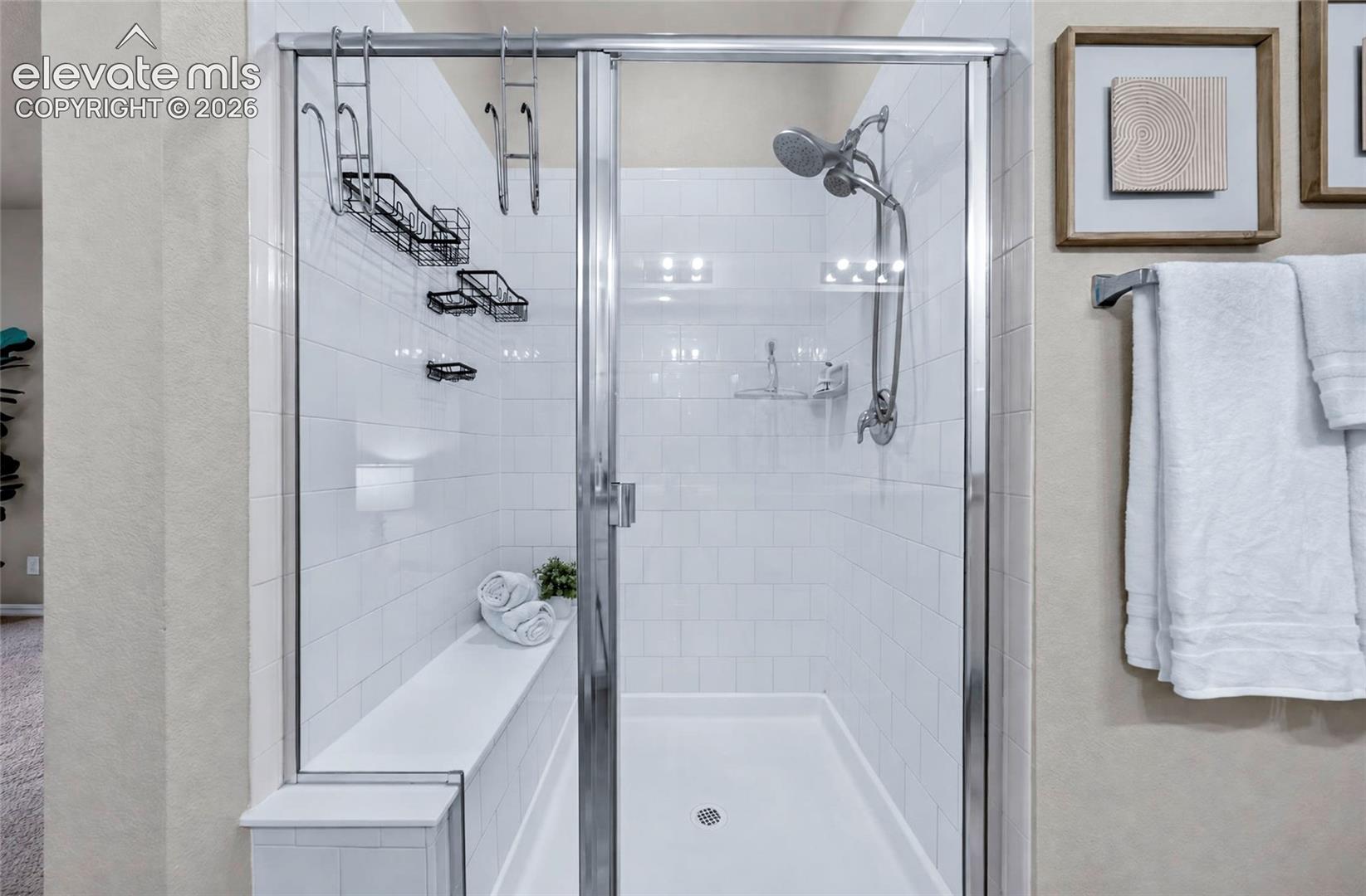 Glass-enclosed shower with subway tile surround, built-in bench, and a modern shower head