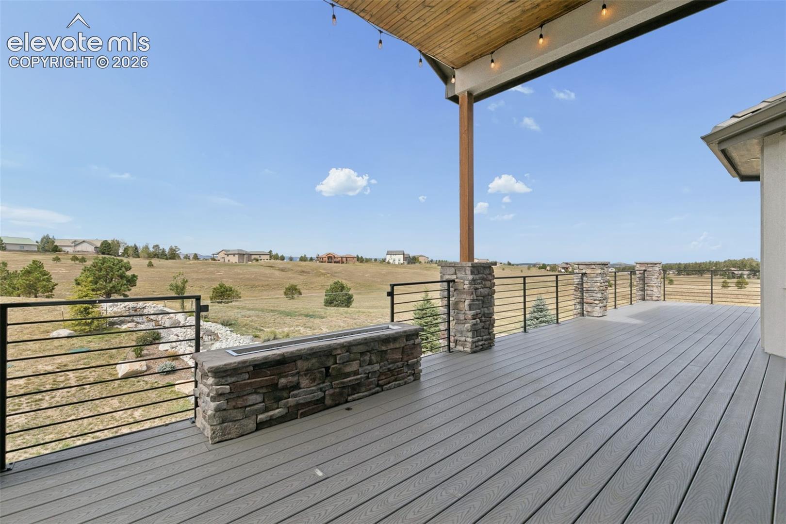 Expansive deck with composite decking, stone-clad pillars, and a built-in stone fire feature