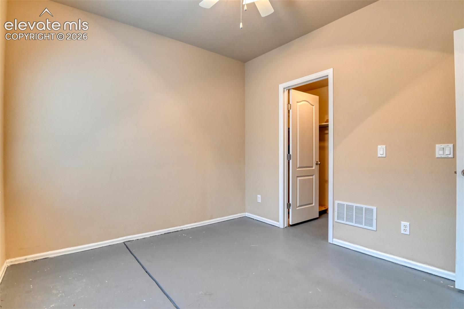Neutral wall tones, ceiling fan, solid-core interior door, and smooth-finish flooring