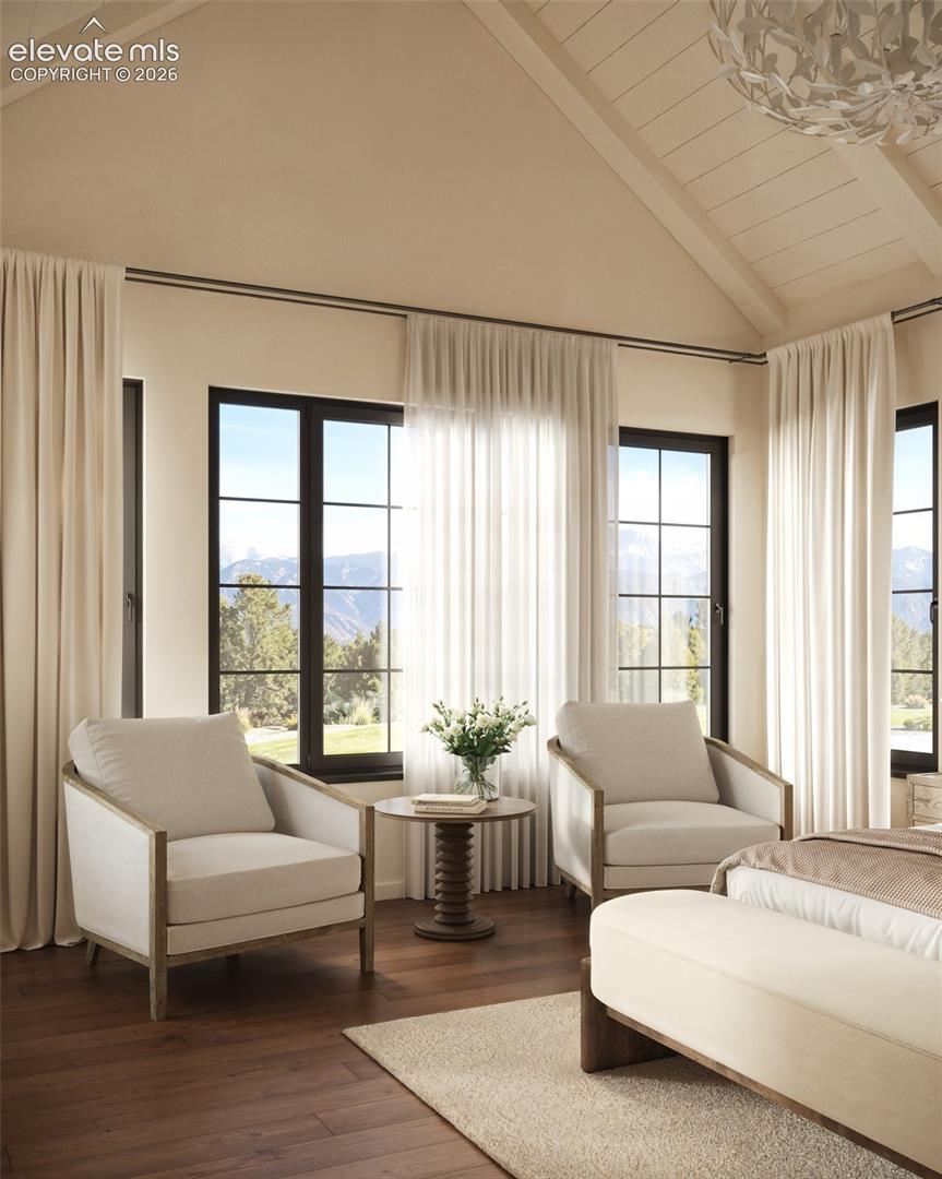 Vaulted ceiling with exposed beams, wood-finish flooring, and multi-pane windows featuring mountain scenery