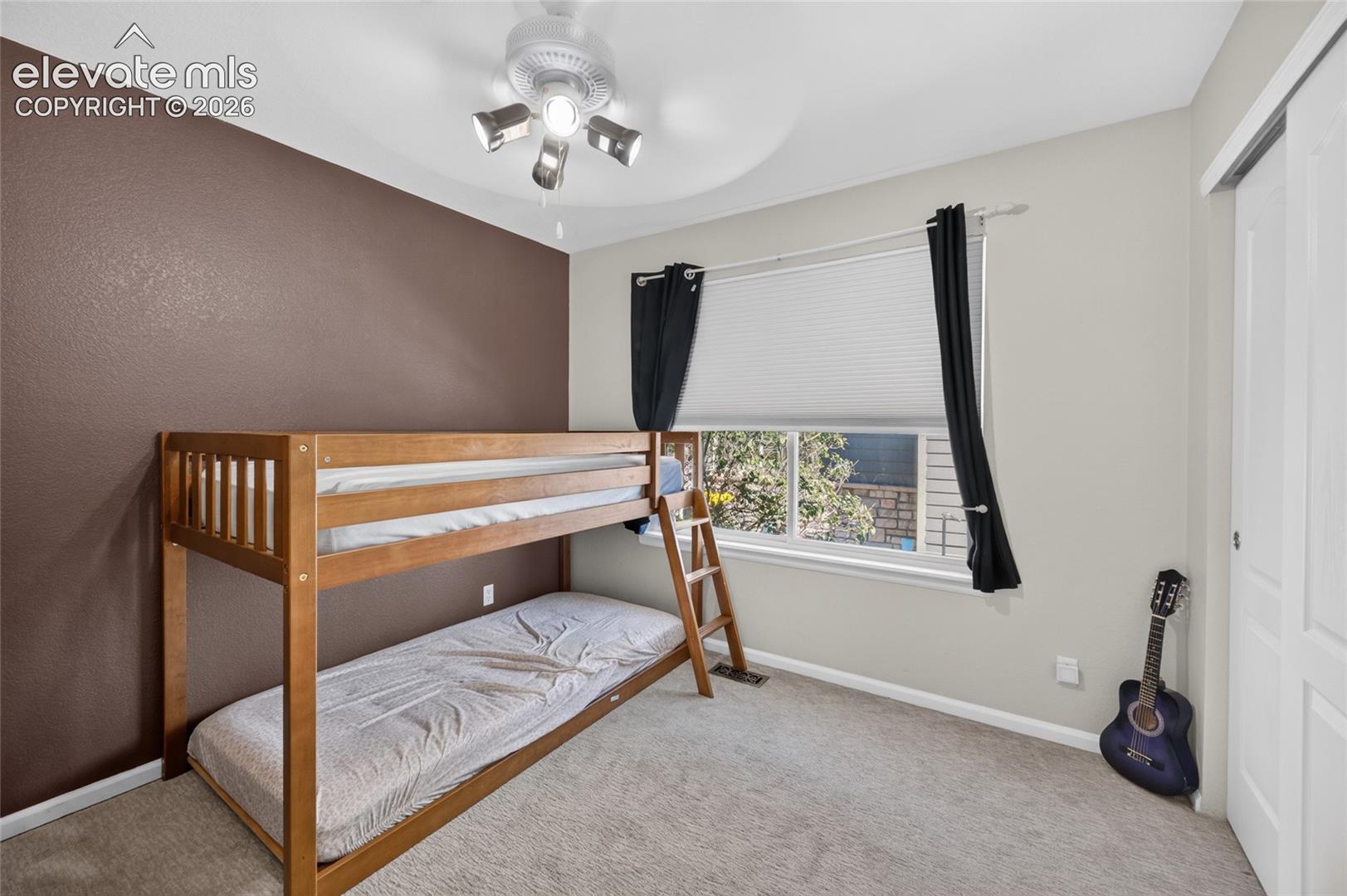 Neutral-toned room featuring a dark brown accent wall, carpeting, multi-light ceiling fixture, and a sliding closet door