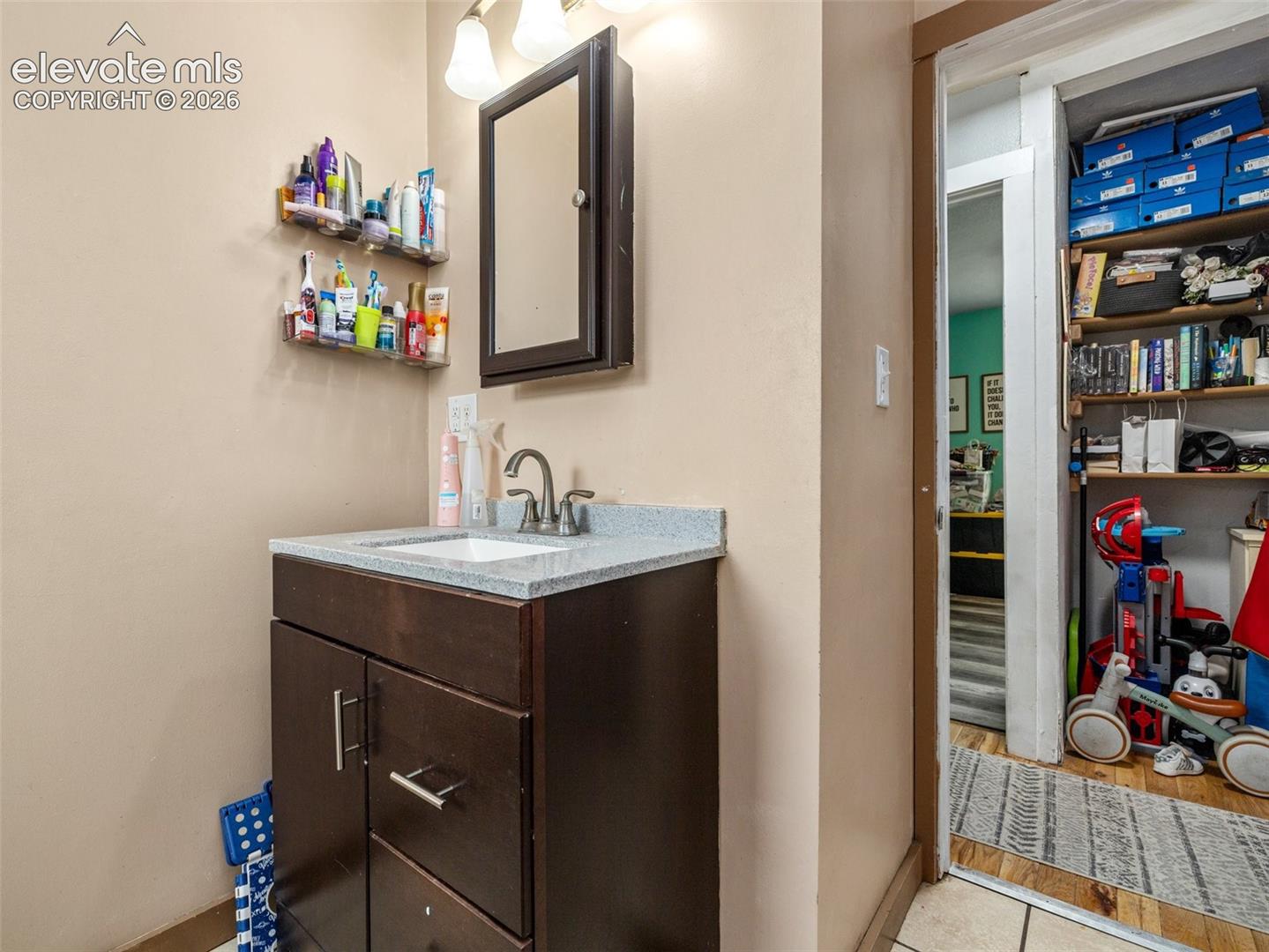 Bathroom vanity with a gray granite-style countertop, integrated sink, and dark wood-finish cabinetry