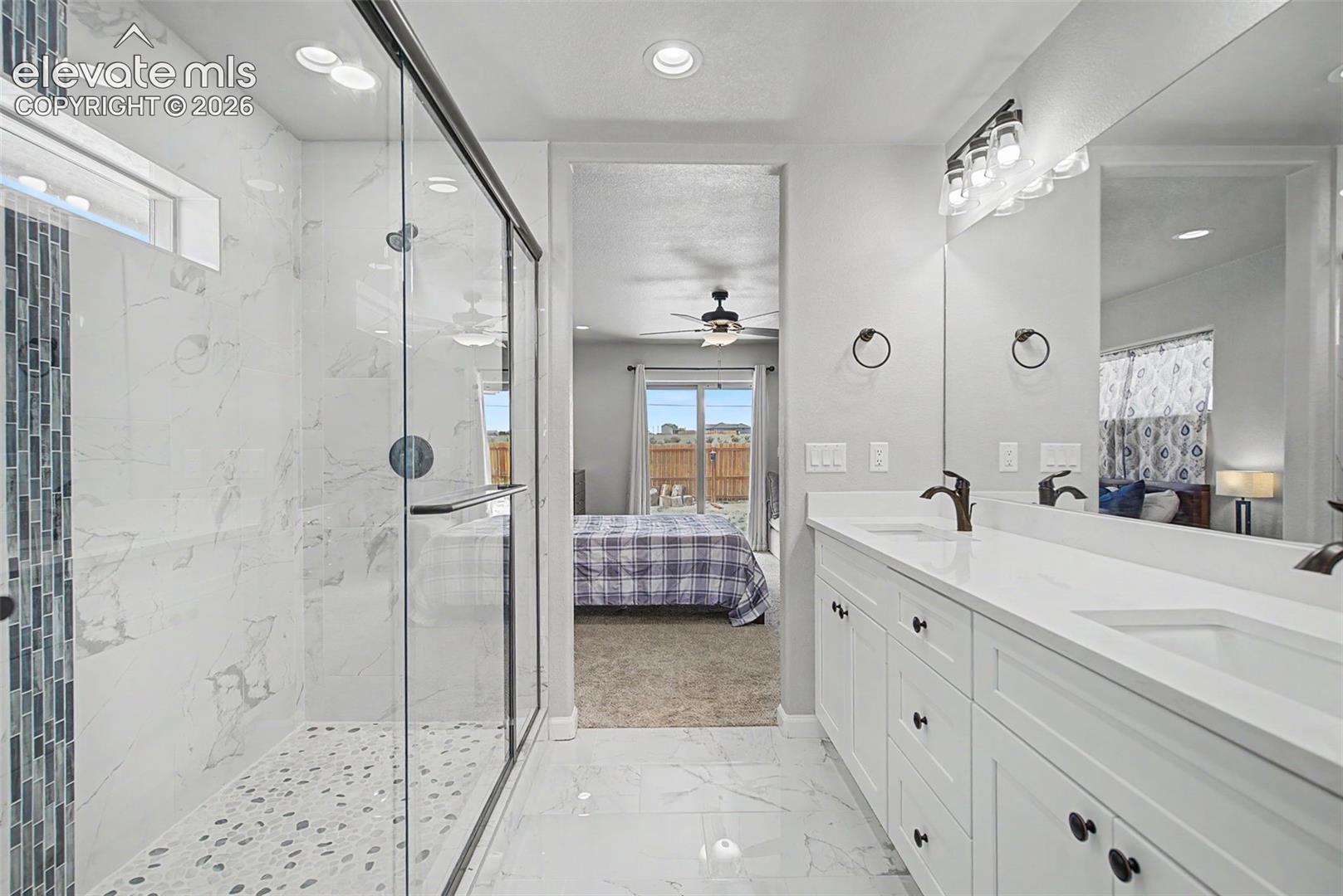Spacious bathroom featuring a dual vanity with white cabinetry, a large mirror, and a walk-in shower with a glass enclosure