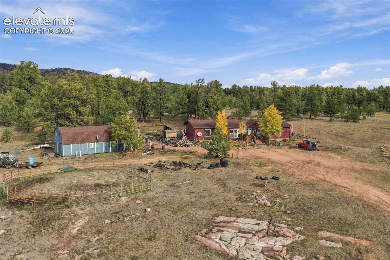 Expansive acreage featuring a detached storage structure, metal livestock fencing, unimproved grounds, and a mountain backdrop