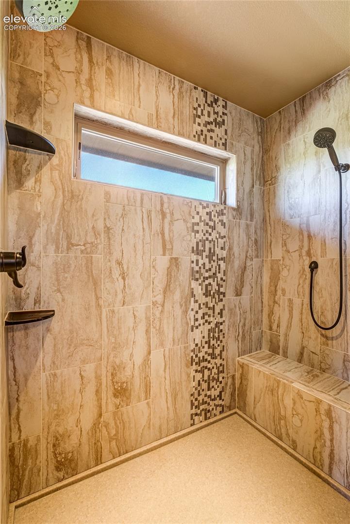 The spa-inspired primary shower features beautiful tilework, dual shower heads + a built-in bench, creating a luxurious space to unwind and recharge within the privacy of the primary suite.