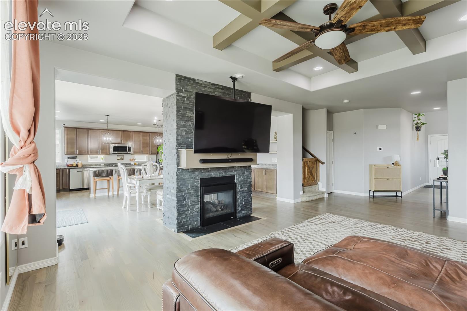 Open-concept living area featuring wood-finish flooring and a coffered ceiling with a wood-blade ceiling fan