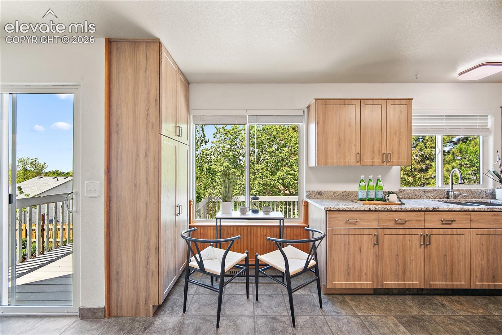 Kitchen featuring light wood-finish cabinetry, speckled granite countertops, and an undermount sink
