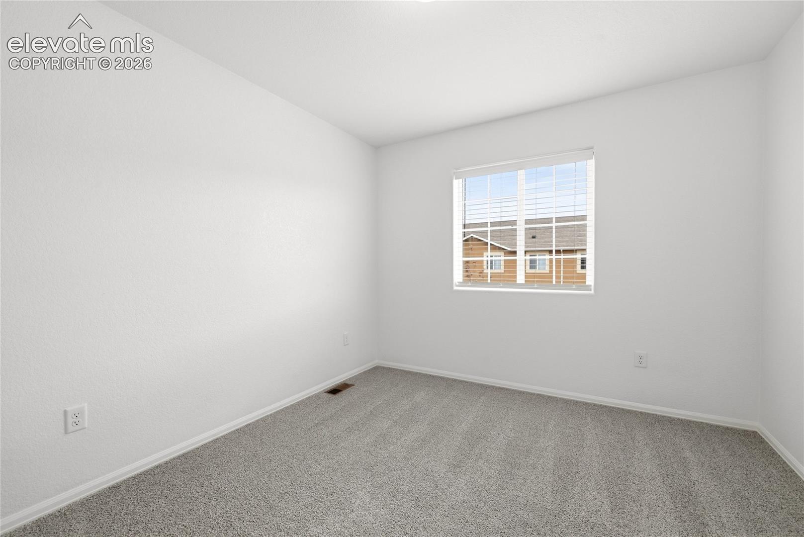 Neutral-toned carpeted flooring, white wall finish, and a single-pane window featuring integrated horizontal blinds