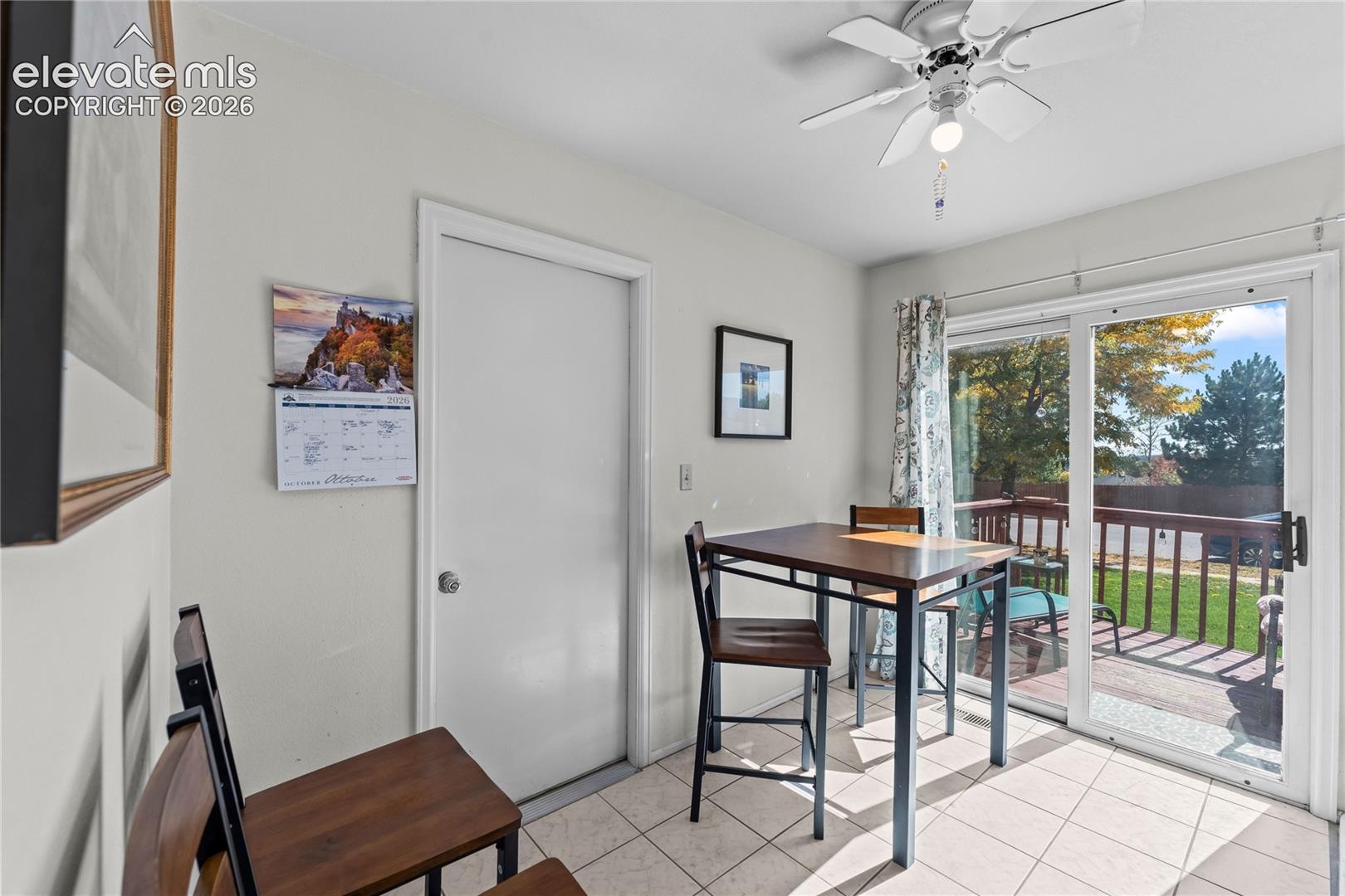 White tiled flooring, ceiling fan with light fixture, sliding glass door, and outdoor deck