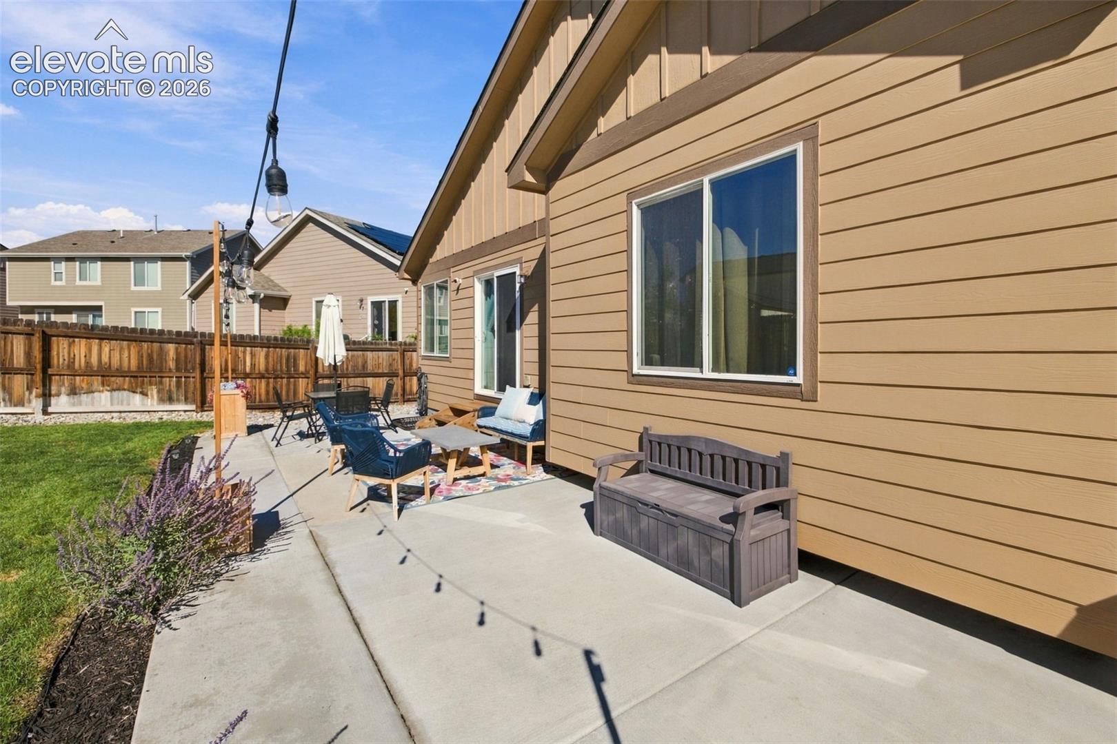 Exterior rear elevation featuring horizontal lap siding, a concrete patio, and a wood privacy fence