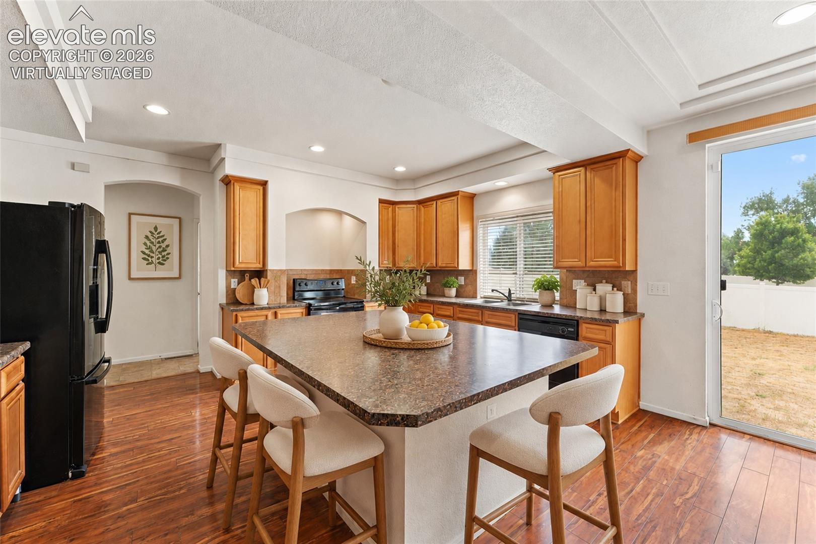 Virtually Staged Kitchen featuring wood-finish cabinetry, central island with a spacious countertop, wood-finish flooring, and sliding glass doors