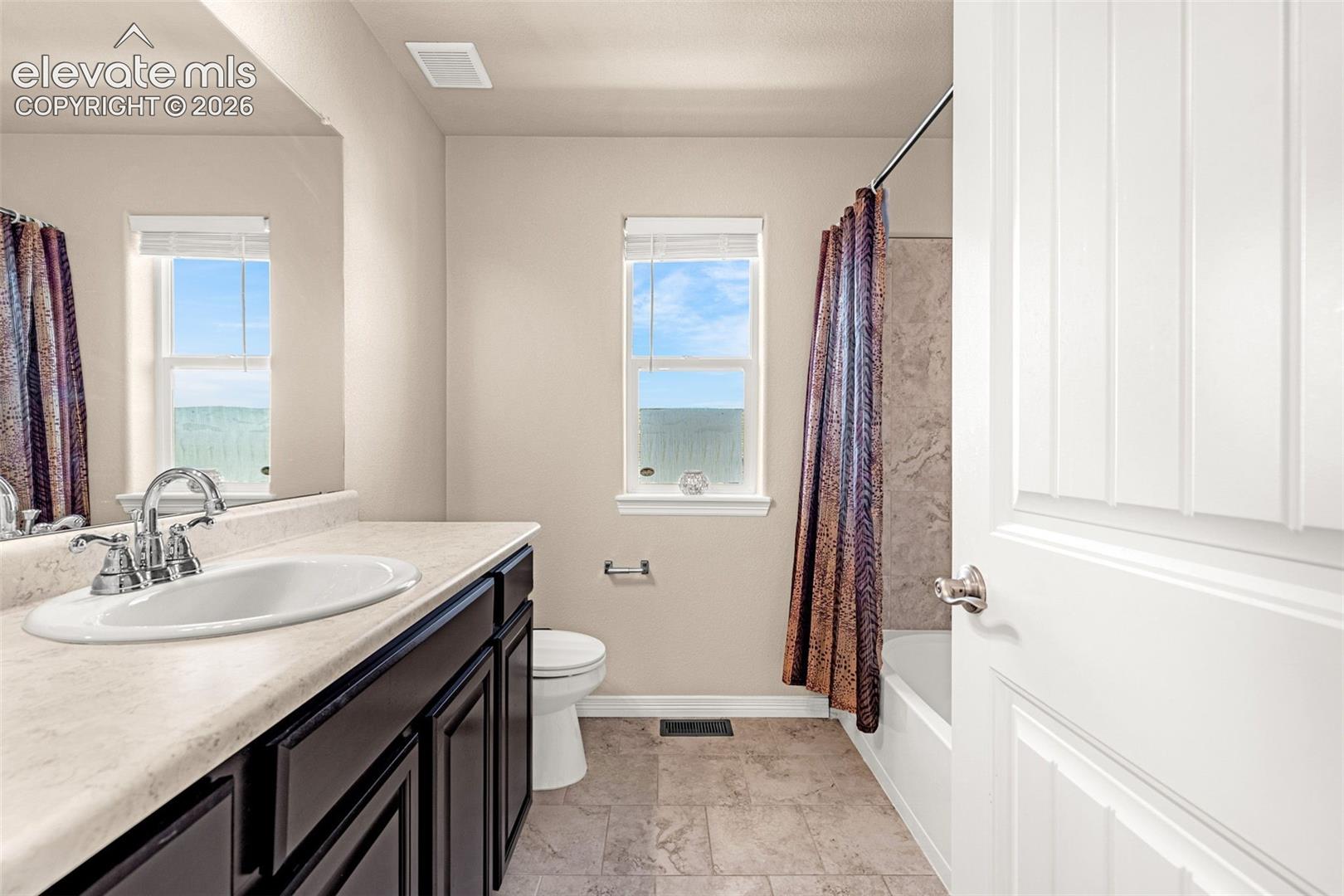Vanity with integrated sink, dark wood-finish cabinetry, and chrome fixtures