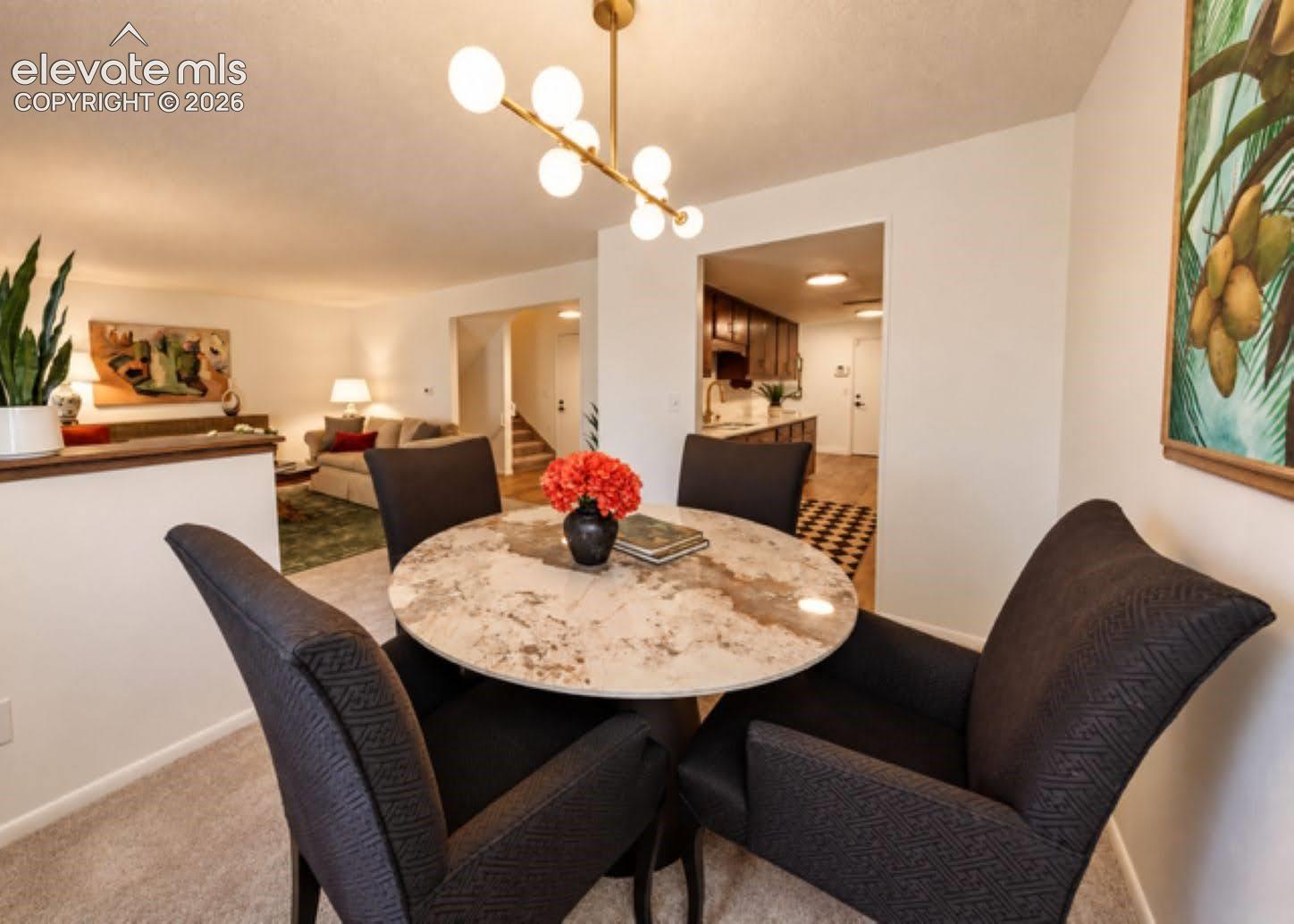 Dining area featuring a contemporary multi-globe brass chandelier and neutral carpeting