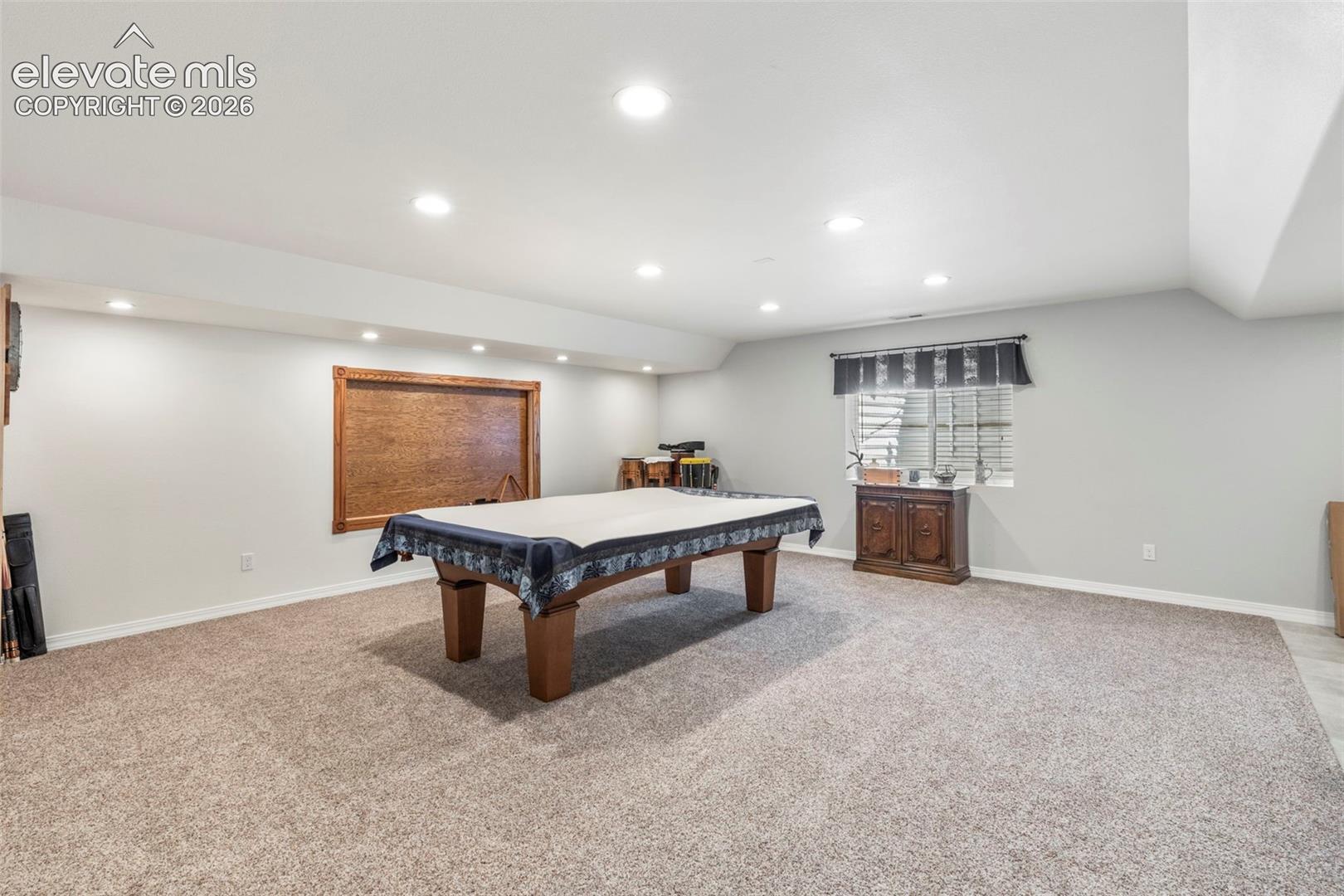 Spacious room featuring recessed lighting, a large window with blinds, and carpeted flooring
