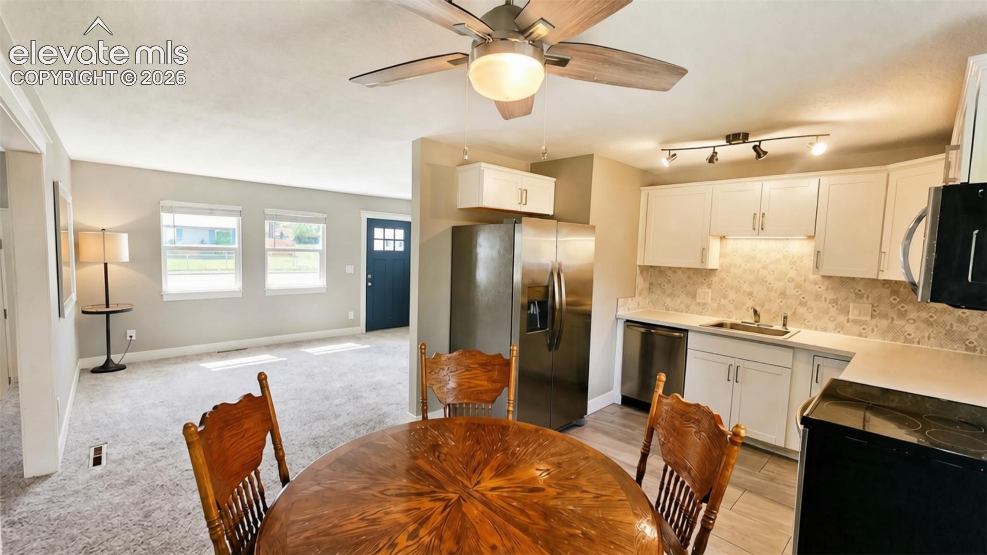 Kitchen featuring white cabinetry, stainless steel appliances, a tile backsplash, and LVP flooring