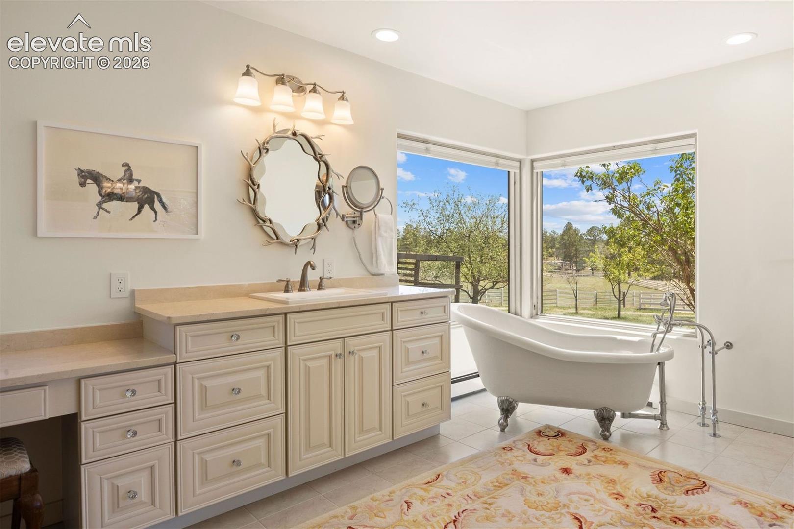 Primary bathroom one with claw-foot soaking tub nestled by two large corner picture windows framing views of the Aspen trees and pastures.