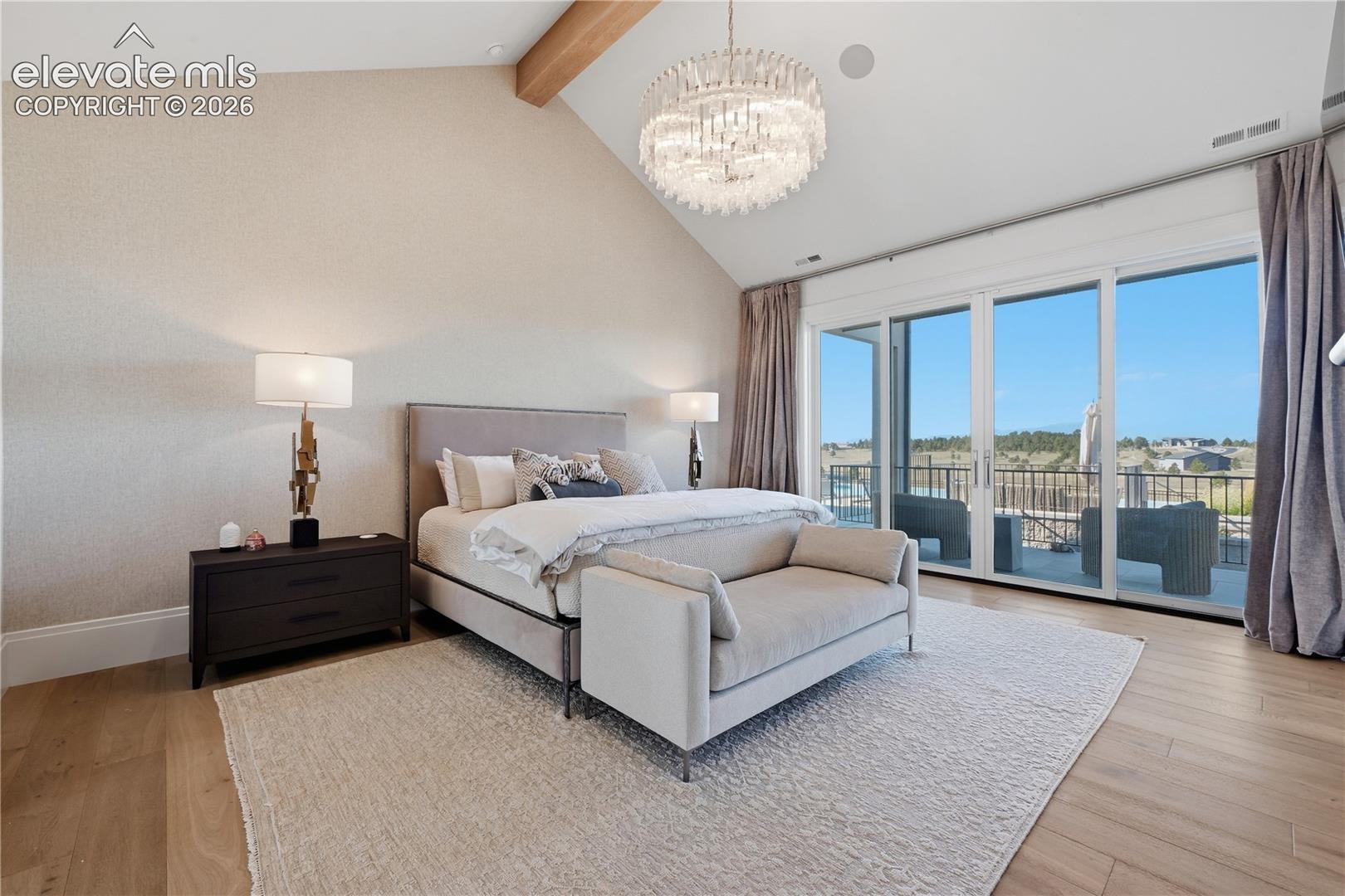 Vaulted ceilings with decorative wood-finish beam, expansive floor-to-ceiling glass sliding doors, and wood-finish flooring