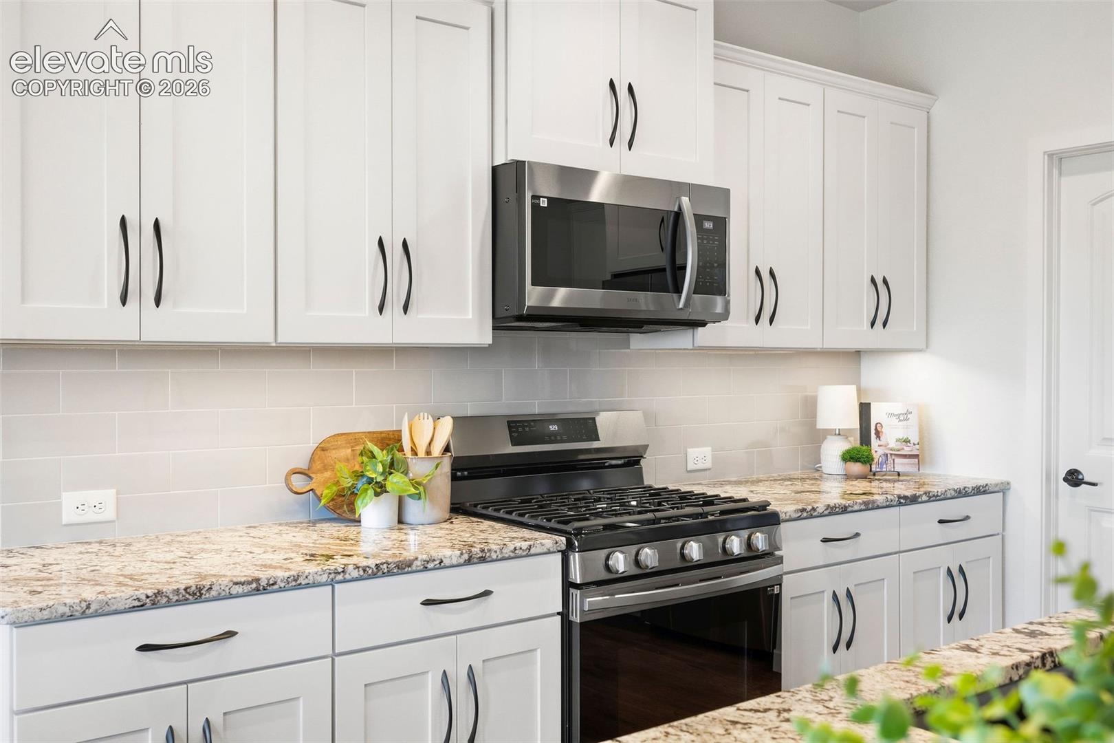The appliances include a five-burner gas range with an overhead vent/microwave, an elegant subway tile backsplash and lots of storage in the upgraded cabinets. 