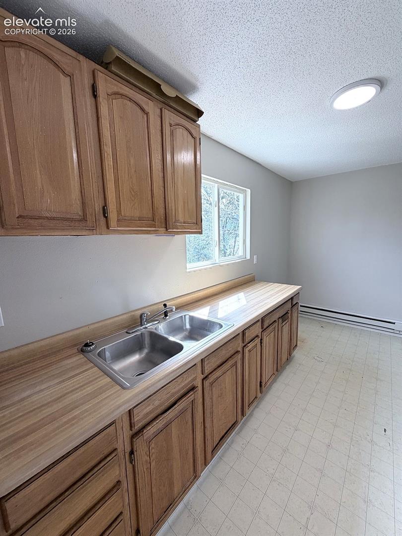 Wood-finish cabinetry with a double basin stainless steel sink, a wood-finish countertop, and a window