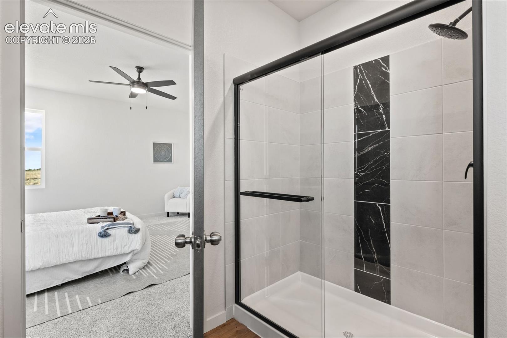 Shower with a sliding glass door, black accent tile, and a rainfall showerhead
