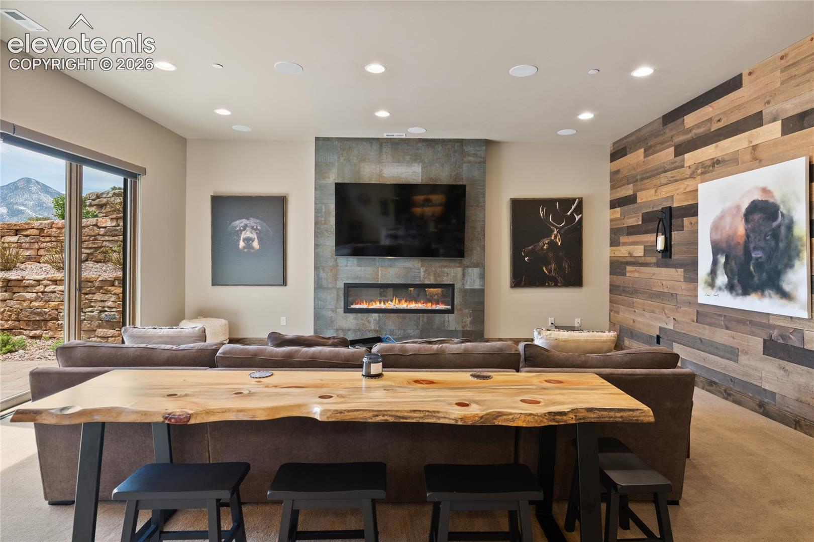 Movie night just got an upgrade. Lower-level theater area with linear gas fireplace, surround sound, custom wood accents, and walk-out access to the patio.