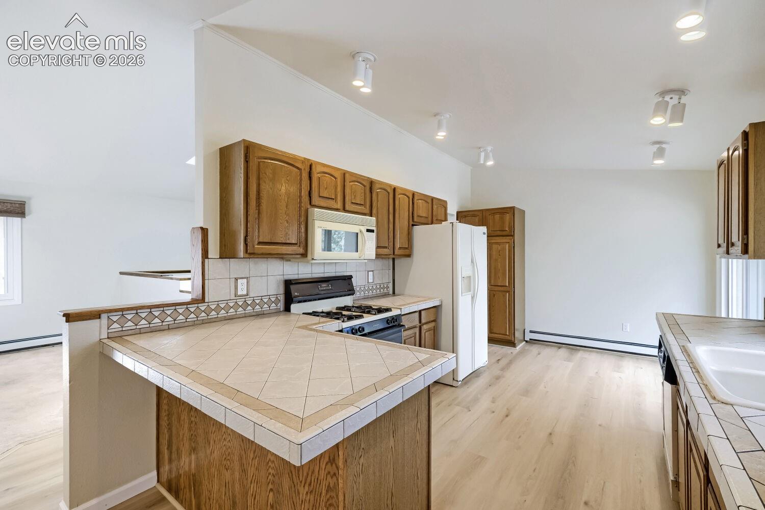 Kitchen with wood-finish cabinetry, tile countertops, and stainless steel sink