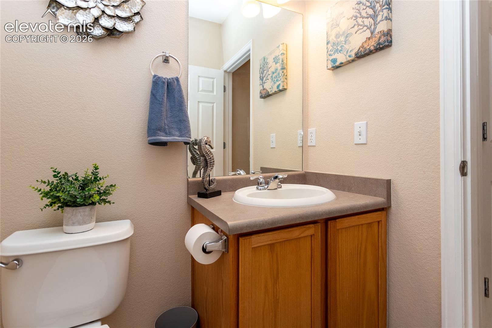The half-bathroom includes an oak vanity sink cabinet and clean fixtures