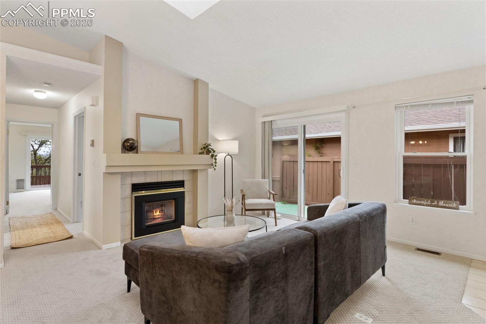 This living area features a fireplace with a mantel, light-colored carpeting, and a glass sliding door leading to an outdoor space