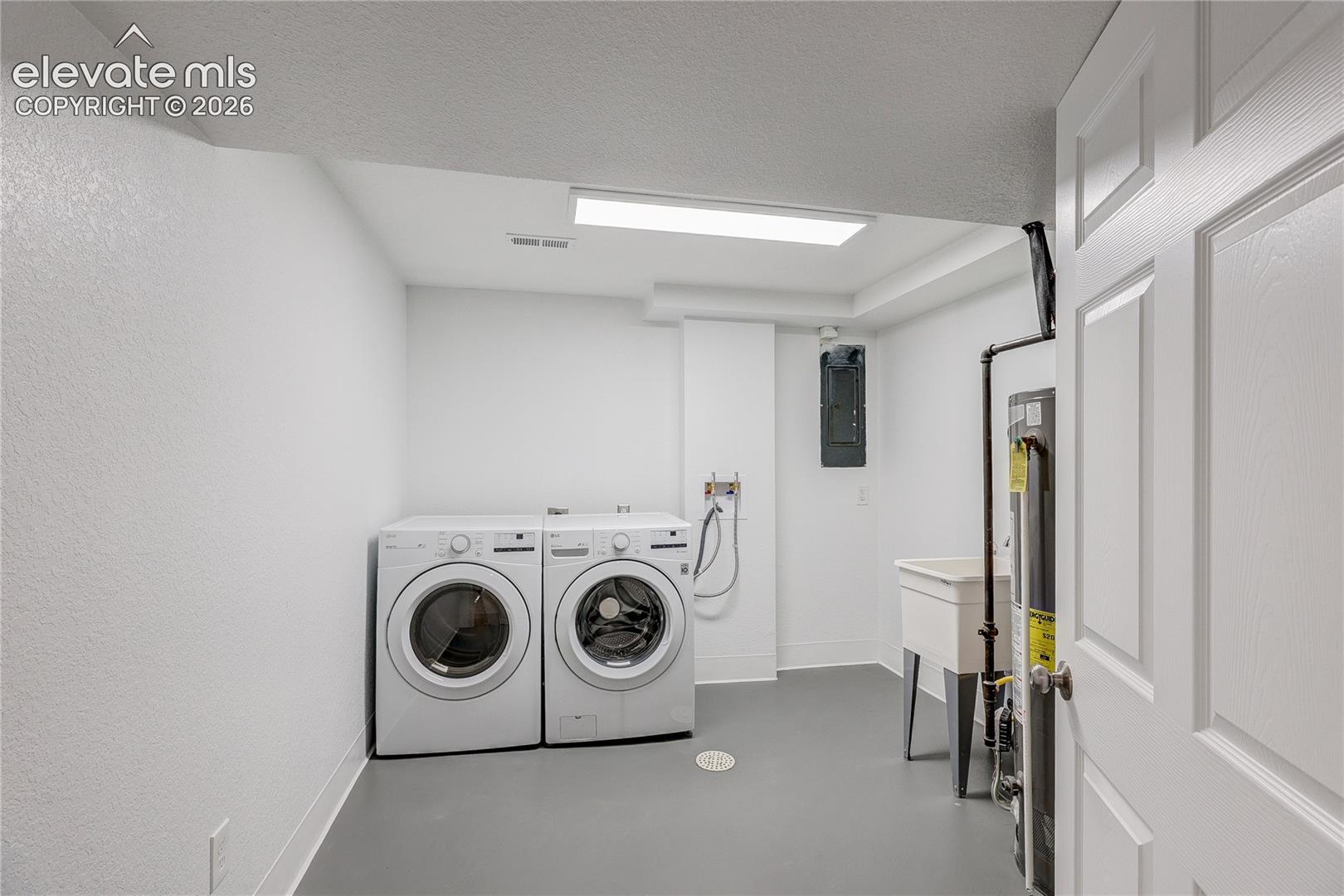 Utility area featuring a basin sink, floor drain, neutral-toned flooring, and overhead flush-mount lighting